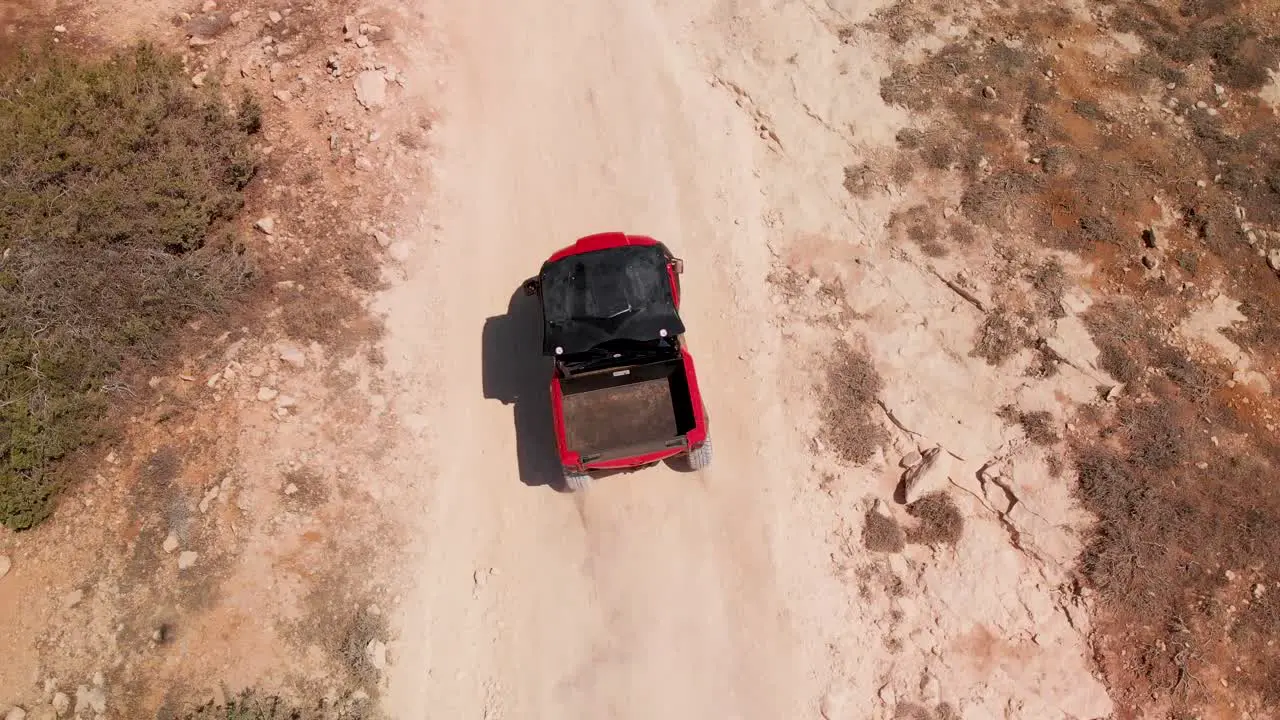 Close tracking shot looking down on a four wheeler dune buggy driving fast on a dirt road