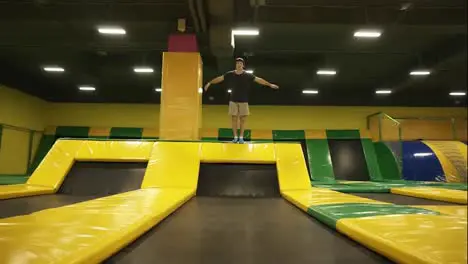 Slowmotion footage of a young male athlete having fun jumping on professional trampoline doing somersaults