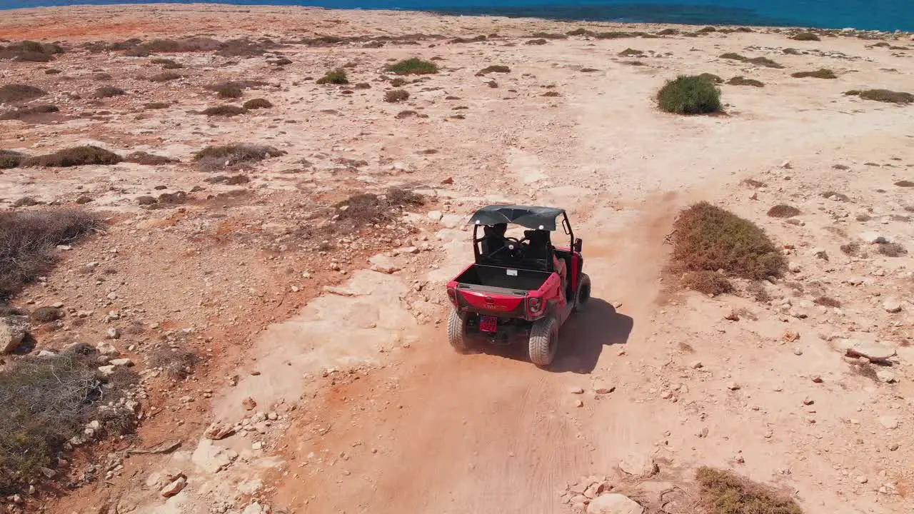 A couple speed off across rocky terrain in a four wheeler while off road