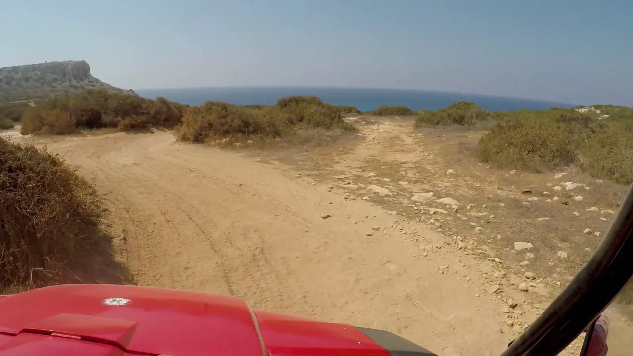 Point of view driving a four runner ATV in Cavo Greco towards the blue sea coast and mountains