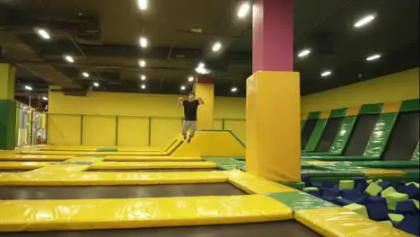 Young spotive athlete excellently trained jums over trampoline sections performing body twists