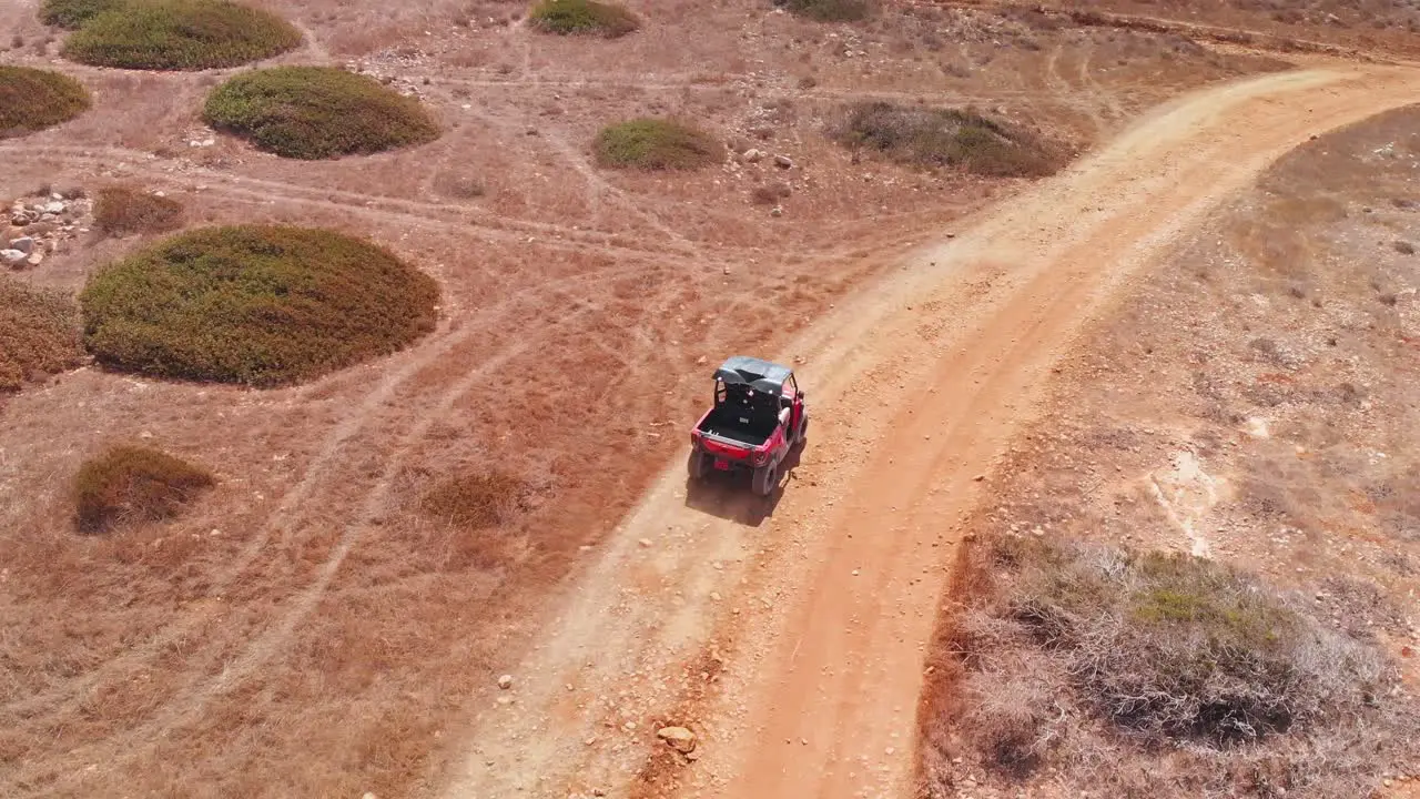 Tracking shot following a four wheeler racing through dessert dirt paths