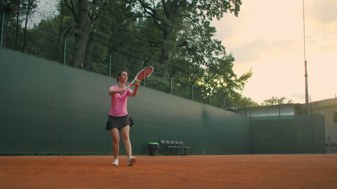 For tennis training a girl stands on the central service line Bangs the ball on the court Serve Wide shot