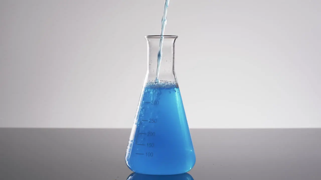 Video of glass laboratory beaker with blue liquid with copy space on white background