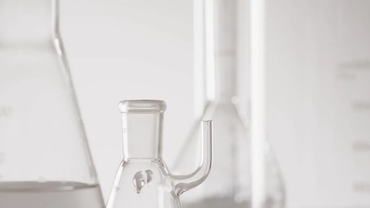 Video of close up of glass laboratory beakers and dishes with copy space on white background