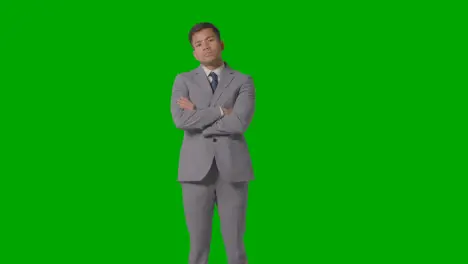 Three Quarter Length Portrait Of Serious Businessman In Suit Folding Arms Against Green Screen 