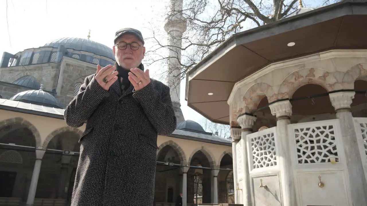 Man praying in front of mosque