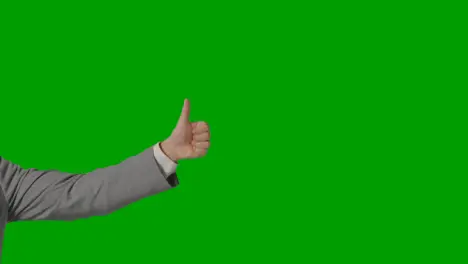 Close Up Of Arm Of Businessman In Suit Giving Thumbs Up Gesture Against Green Screen 