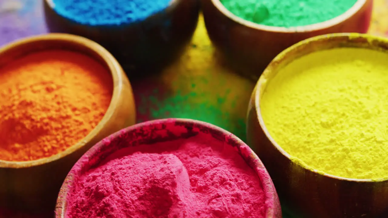 Video of close up of multi coloured powders and bowls with copy space on black background