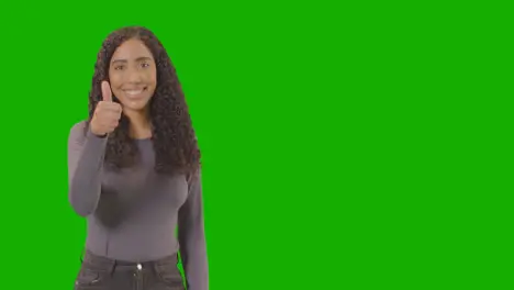 Studio Waist Up Shot Of Woman Giving Thumbs Up Sign Against Green Screen