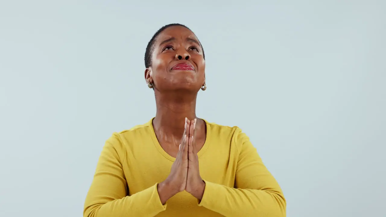 Hands praying and black woman looking up