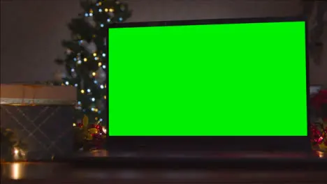 Close Up Shot of Laptop Green Screen On Table In Front of Christmas Themed Backdrop