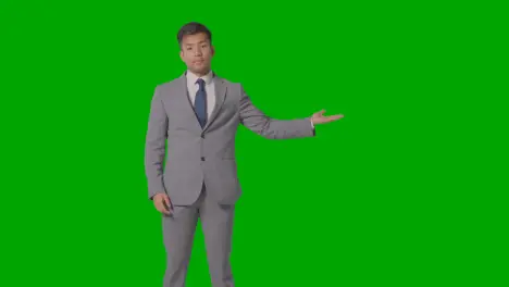 Three Quarter Length Shot Of Businessman In Suit Presenting Or Showing Against Green Screen 1