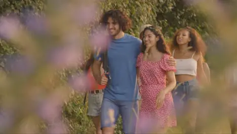 Pull Focus Shot of Group of Friends Walking Along Rural Countryside Path