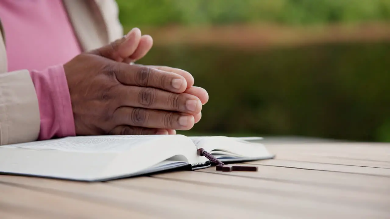 Praying bible and hands of person in garden