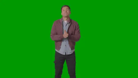 Portrait Of Casually Dressed Smiling Young Man Wearing Jacket Against Green Screen 