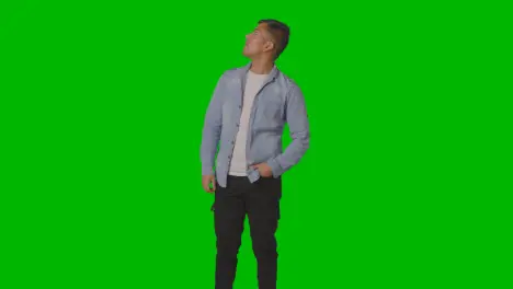 Portrait Of Casually Dressed Smiling Young Man Looking Around Against Green Screen 1