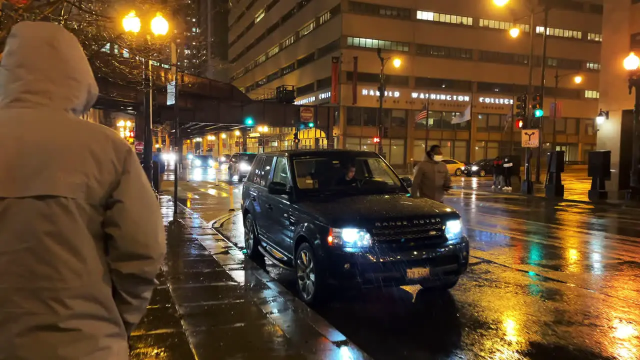 Anonymous man in white coat and hoodie strolling downtown chicago at rainy night