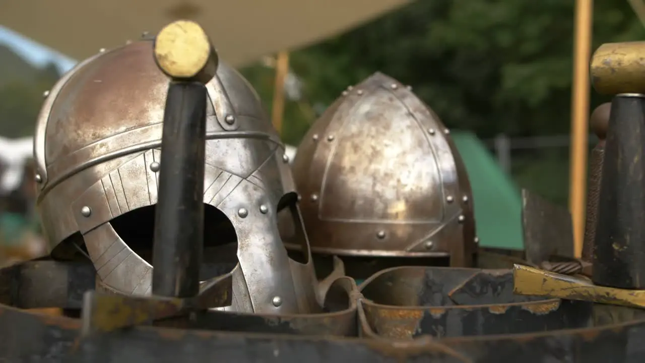 Two viking helmets and swords on showcase on outdoor fair on sunny summer day right circular slider shot