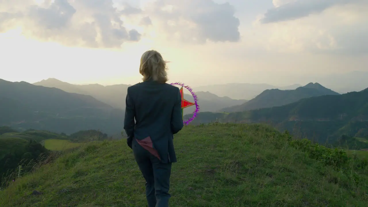 Slow motion shot of a woman walking holding a star lantern at a hillside