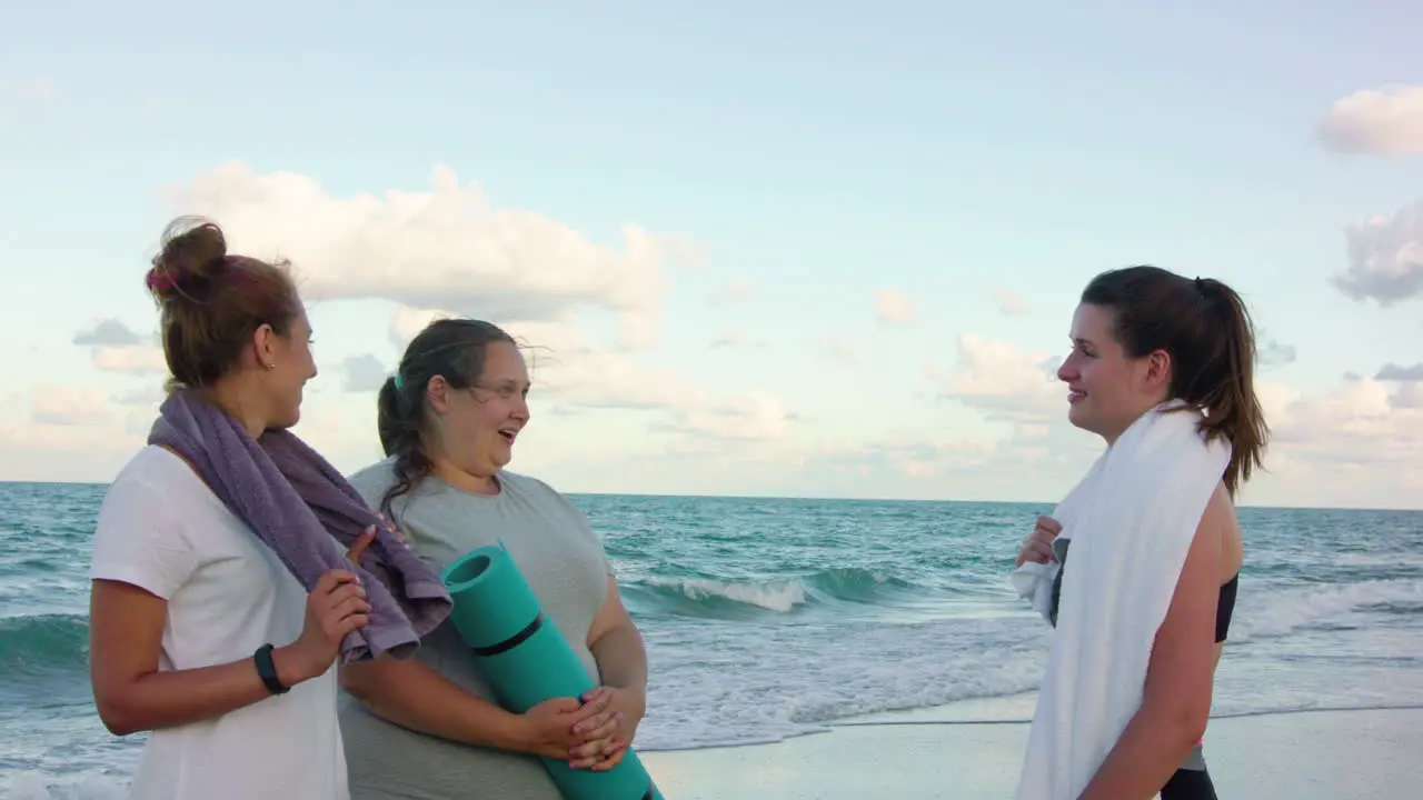 Three girls in sportive clothes talking on the beach