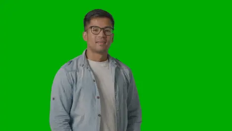 Portrait Of Casually Dressed Smiling Young Man Wearing Glasses Against Green Screen 