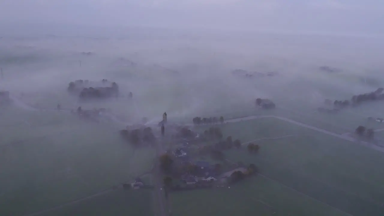 Wide shot of Kerk van Hichtum with low fog during sunrise aerial