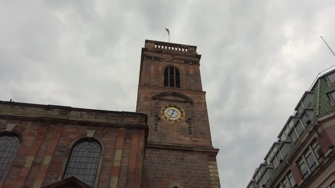 Manchester UK St Ann's Church with English flag waving in the wind on a cloudy day