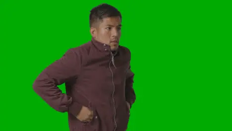 Portrait Of Cold Shivering Casually Dressed Young Man Doing Up Coat Against Green Screen 1