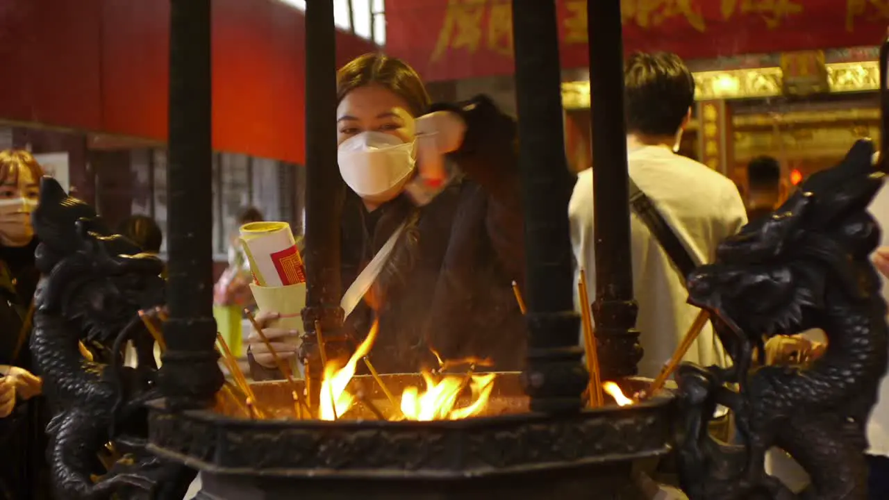 Asian men and women performing ritual offerings in incense pot at temple for love and fertility