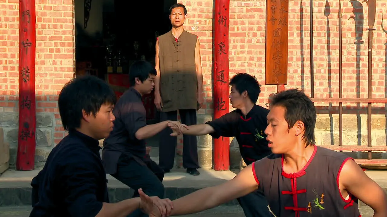 Master of ancient Chinese martial arts guides hand movements of boys