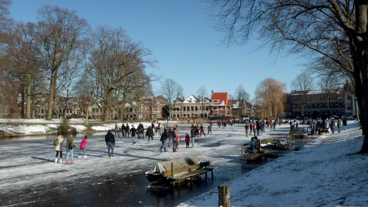 People ice skating on a frozen canal in Leiden the Netherlands on a sunny winter day during the pandemic