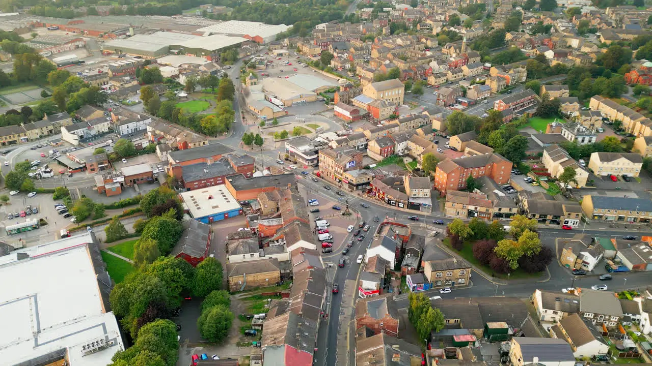 A drone records Heckmondwike UK with industrial buildings bustling streets and the old town center on a summer evening