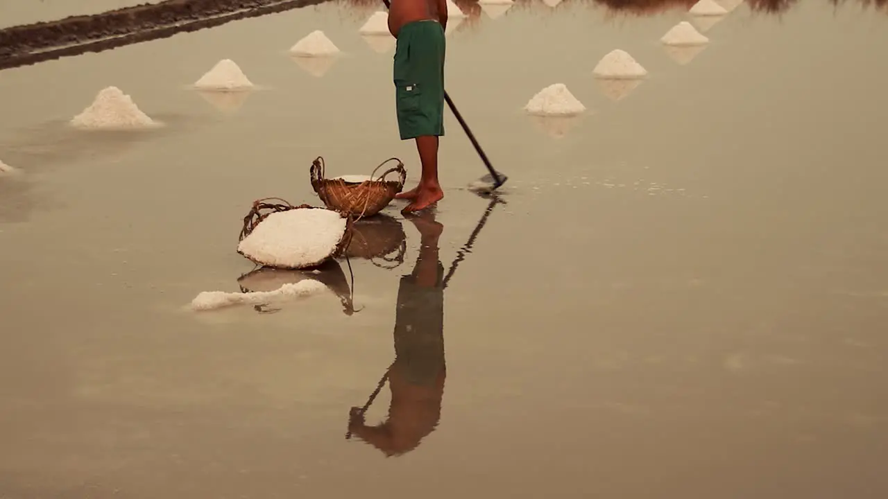 Low section shot of a salt field worker harvesting salt in Kampot Cambodia