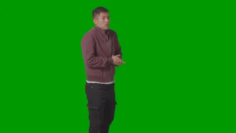 Three Quarter Length Portrait Of Cold Shivering Casually Dressed Young Man Doing Up Coat Against Green Screen 1