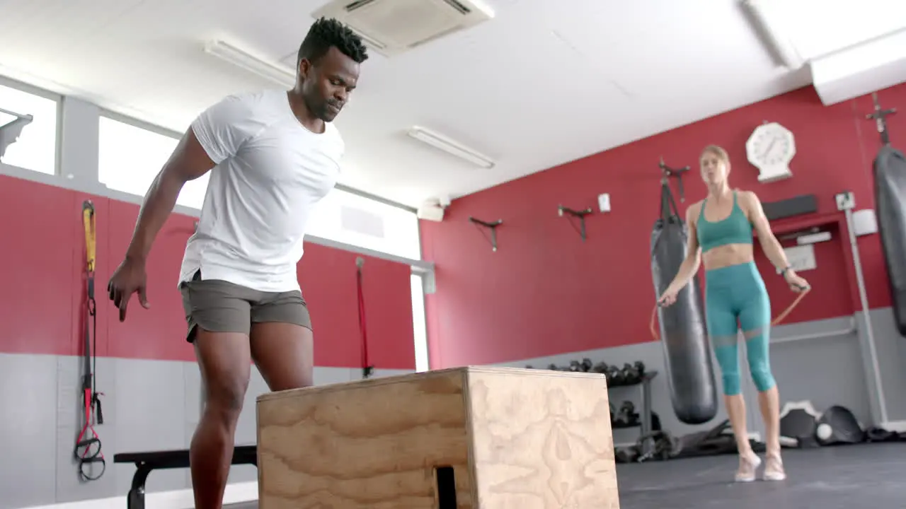 Fit African American man jumps onto a box at the gym