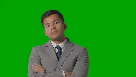 Portrait Of Serious Businessman In Suit Against Green Screen Looking At Camera