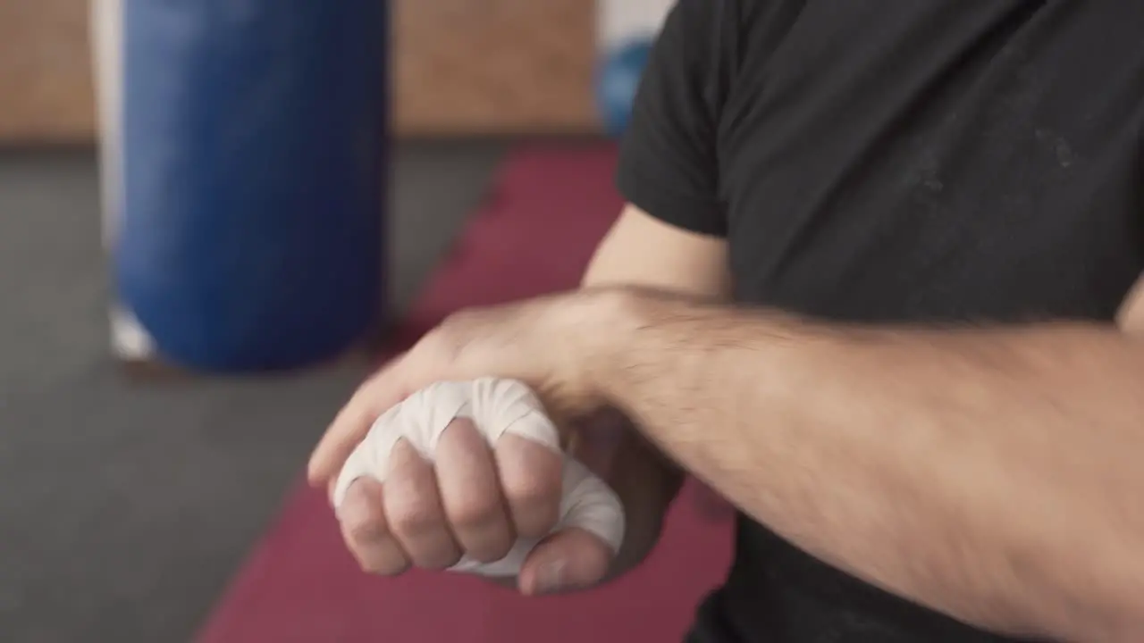 Close-up of a young athletic man wrapping his hand with white box bandage