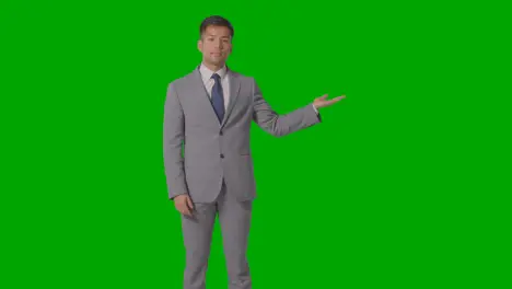 Three Quarter Length Shot Of Businessman In Suit Presenting Or Showing Against Green Screen 3