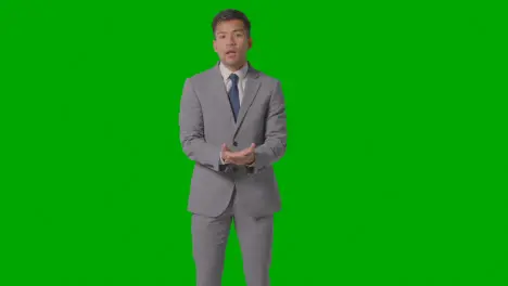 Three Quarter Length Shot Of Angry Businessman In Suit Against Green Screen Talking To Camera