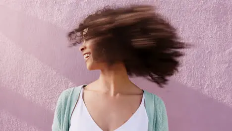 Funky woman shaking natural curly hair on pink