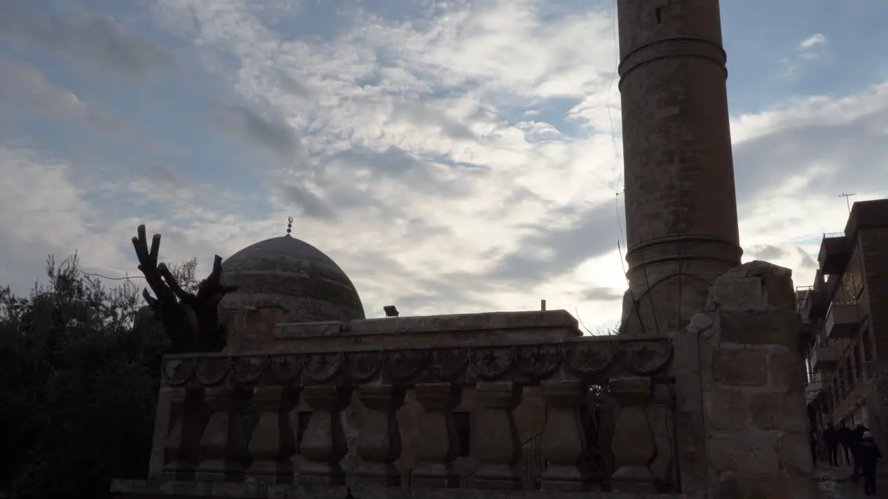 From the lower angle to the top we see the silhouette of the Mardin Great Mosque in the reverse light and behind it the deep blue sky and the clouds that look like cotton