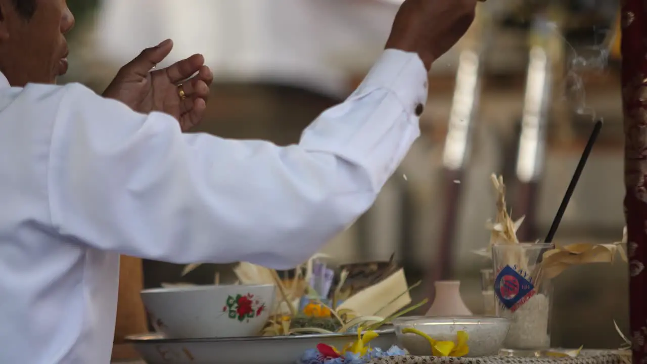 Close up view of Hindu priest performing ceremony and tossing rice offering from altar at temple