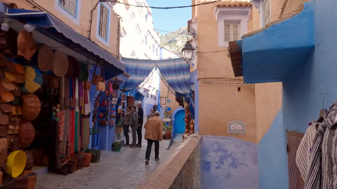 Chefchaouen touristic alleyway with souvenir shops People walking along the narrow street tilt down shot