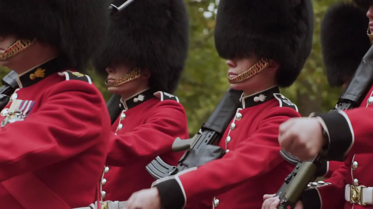 London Queen's Guard contingents of infantry and cavalry soldiers charged with guarding official royal residences in United Kingdom marching in rows handheld close up slow motion