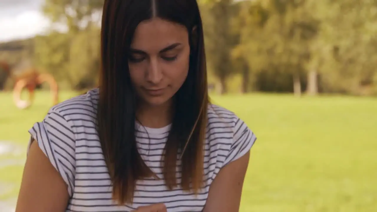 Pretty brunette using tablet in park