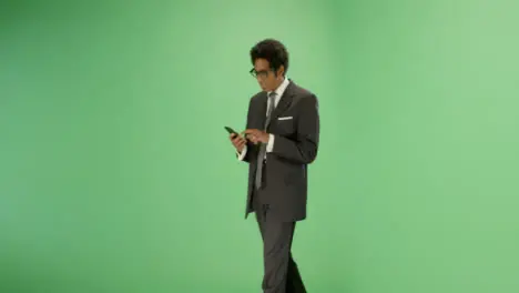 Businessman texting while walking on green screen