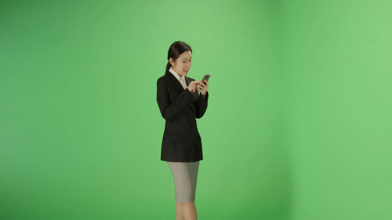 Smiling woman typing on phone with green screen