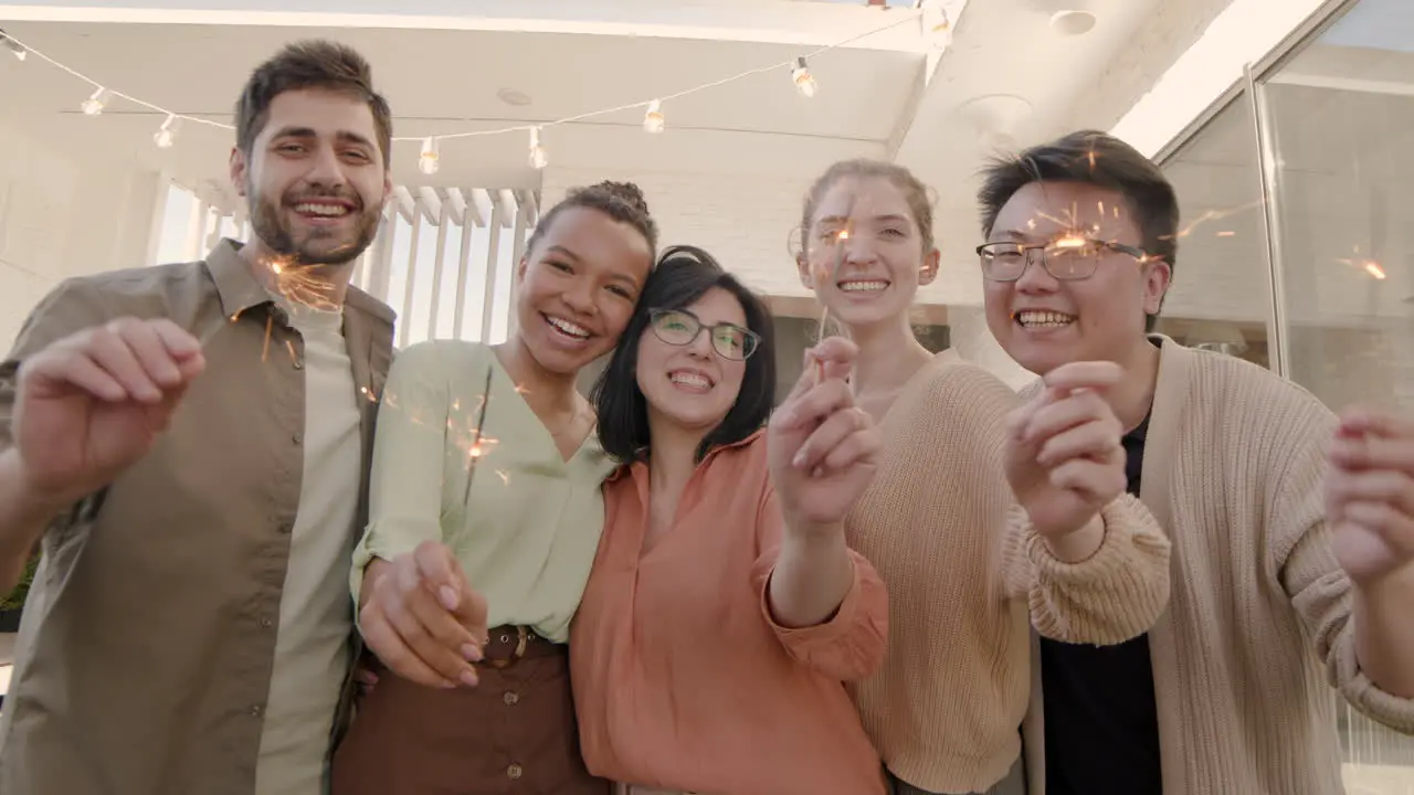 Un Grupo Multiétnico De Amigos Mirando La Cámara Sonriendo Y Sacudiendo Algunas Bengalas 2