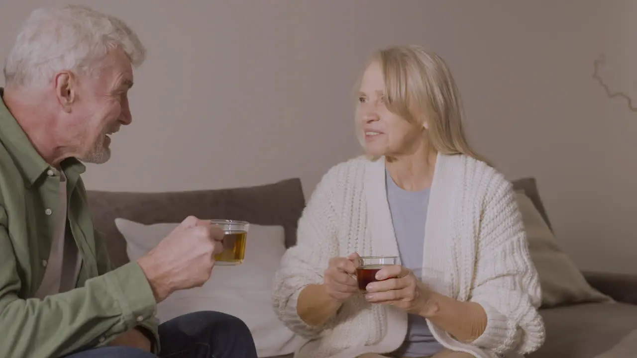 älterer Mann Und Frau Trinken Tee Während Sie Zu Hause Auf Dem Sofa Sitzen